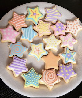 Colorful star-shaped decorated cookies with pastel icing patterns on a white plate