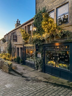 Festive street scene in Haworth with Christmas lights and garlands on historic stone buildings