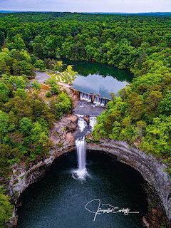 Aerial photo of DeSoto Falls waterfall with green forest and pool above a dam in Alabama