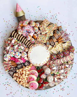 Overhead view of dessert charcuterie board with assorted sweets arranged in a circle around white dipping bowl