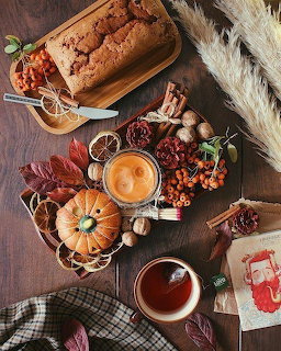 Overhead autumn table with pumpkin, tea, loaf cake, dried oranges, and fall decorations