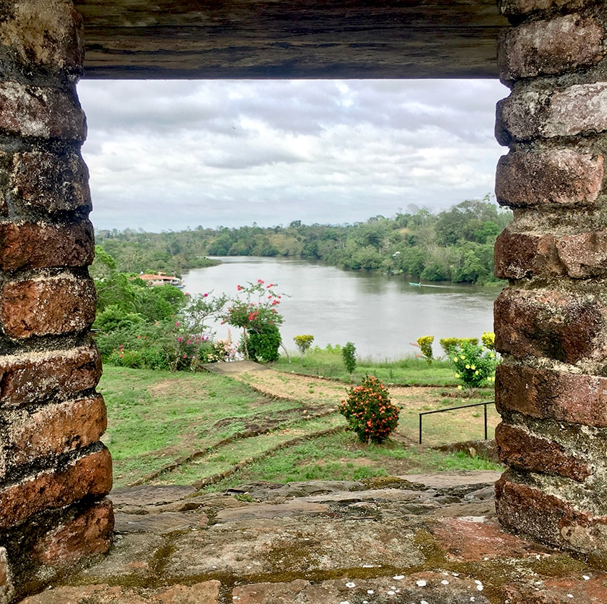 River and green landscape viewed through a rustic stone window opening