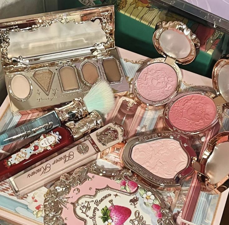Ornate makeup collection with eyeshadow palettes, blush compacts, lip gloss, and brushes arranged together