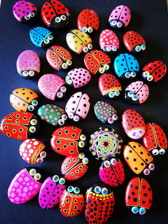 Assortment of hand-painted rocks decorated as colorful ladybugs with various patterns and dots on black background