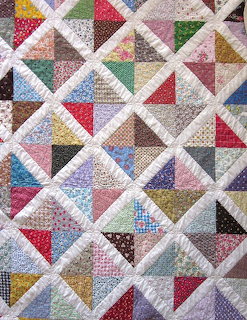 Patchwork quilt with colorful triangle patterns and white lattice design