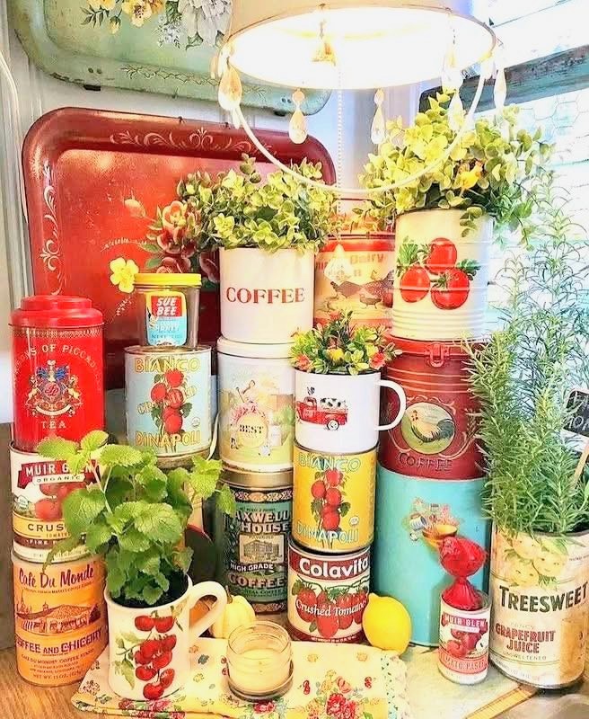 Stacked vintage kitchen tins and canisters with herbs, flowers, and lemons indoors