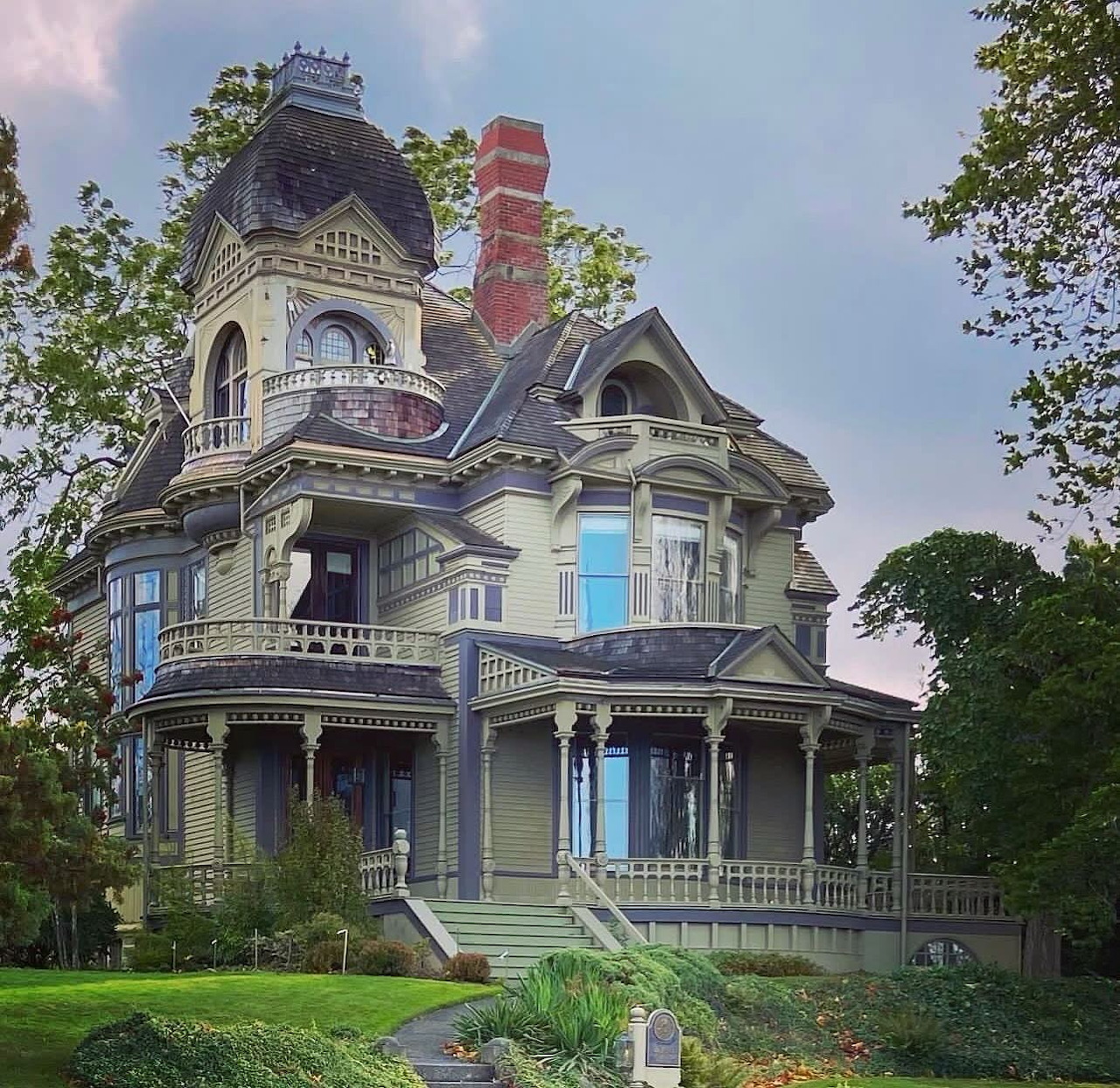 Grand Victorian mansion with turret and wraparound porch on green lawn