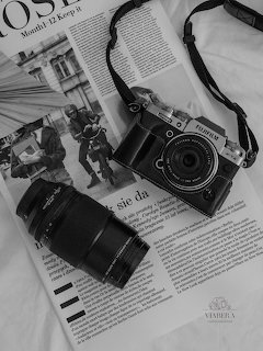 Fujifilm mirrorless camera and zoom lens placed on an open newspaper, black and white photo
