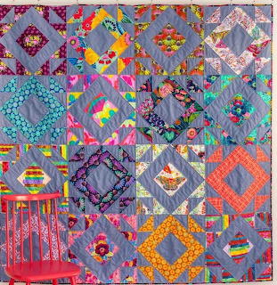Colorful patchwork quilt with geometric and floral patterns in various bright fabrics