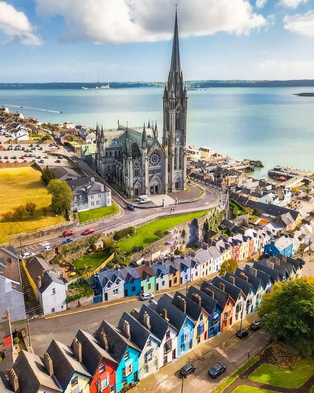 Aerial view of Cobh, Ireland showing St Colman's Cathedral and colorful row houses along the harbor