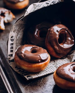 Chocolate glazed donuts on a wooden board with dark background