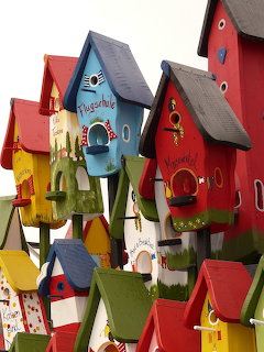 Multiple colorful decorative birdhouses clustered together with red, blue, yellow and green paint