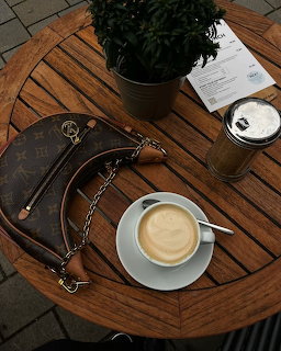 Cup of coffee, takeaway coffee, handbag, and potted plant on a round wooden table