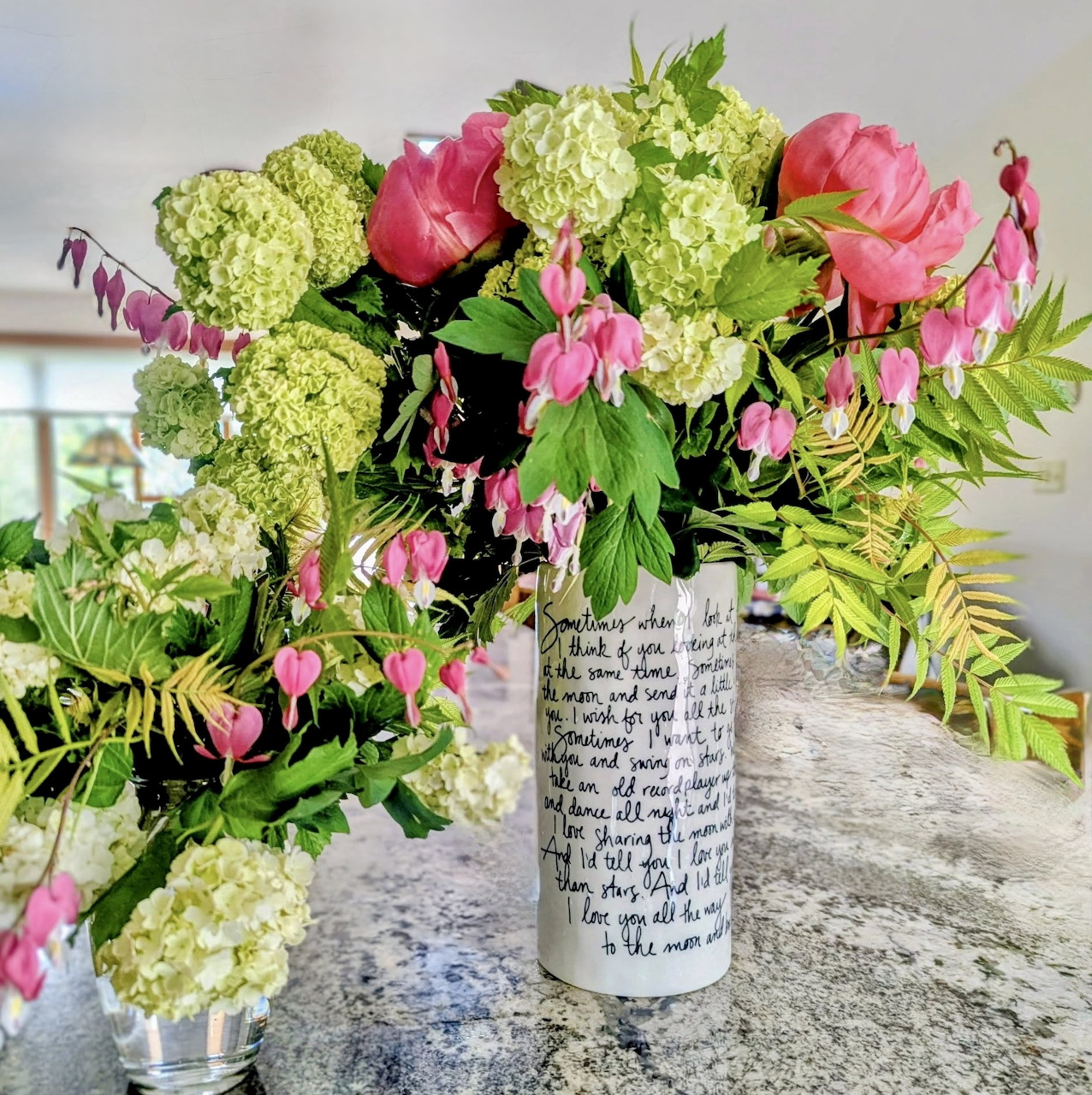 Pink and green flower bouquet in a white vase on a stone table