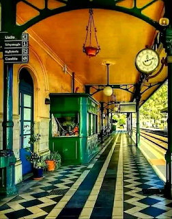 Train platform with checkered floor, yellow arched ceiling, vintage clock and green kiosk in Sicily