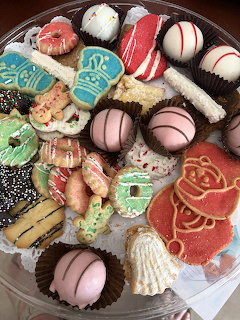 Round platter with assorted Christmas cookies, chocolate truffles, and holiday sweets on white decorative surface