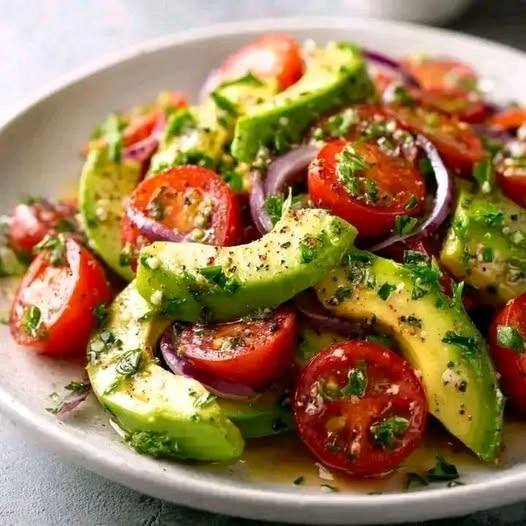 Bowl of avocado and cherry tomato salad with red onion and herbs
