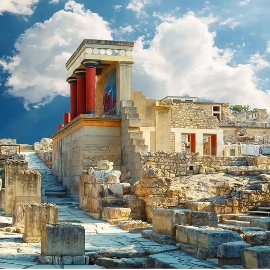 Ruins of Knossos Palace in Crete with red columns and stone walls under a blue sky