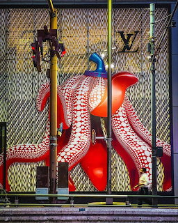 Red octopus tentacles with white suction cups painted on metal mesh gate, urban street art style
