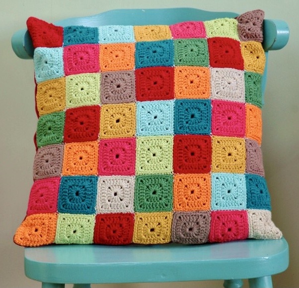 Colorful crocheted granny square cushion on turquoise chair