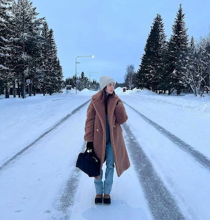 Woman standing on a snowy road between evergreen trees in winter