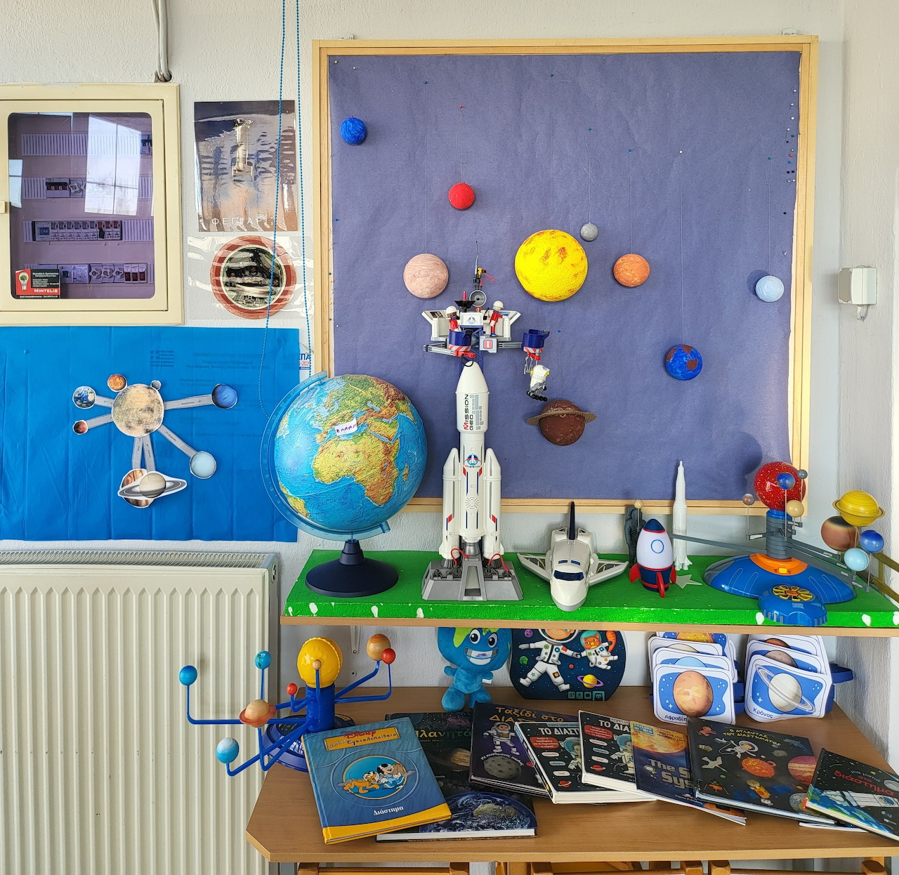 Classroom with space display including solar system model, rocket, globe, and educational materials