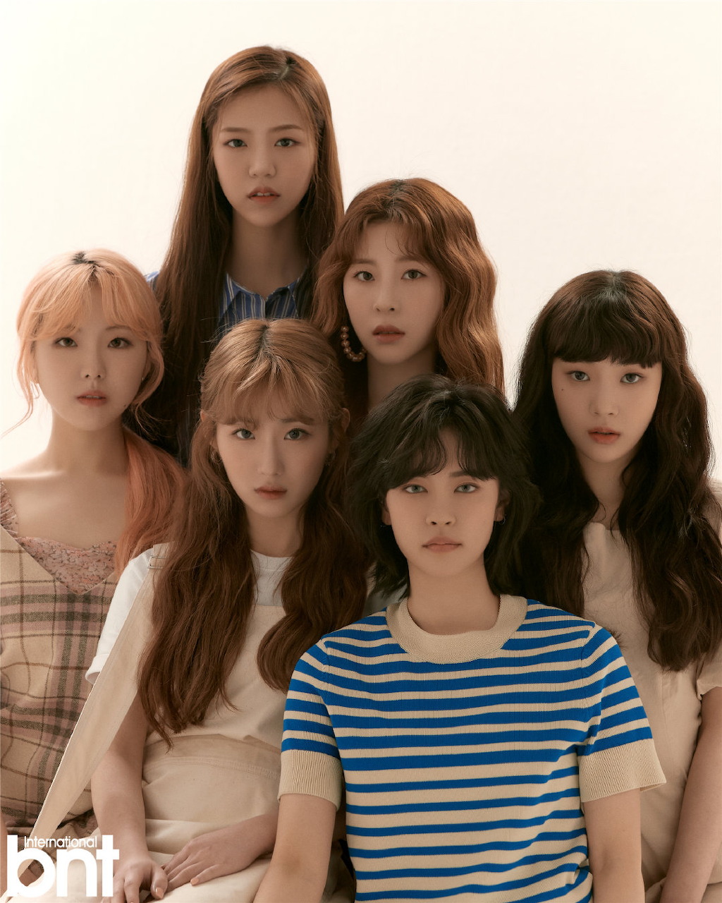 Six young women posing together in a studio portrait with neutral background