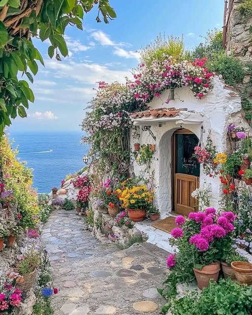White Mediterranean villa entrance with vibrant flowers and ocean view