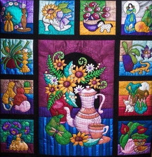 Colorful quilt with central floral teapot design surrounded by decorative border blocks