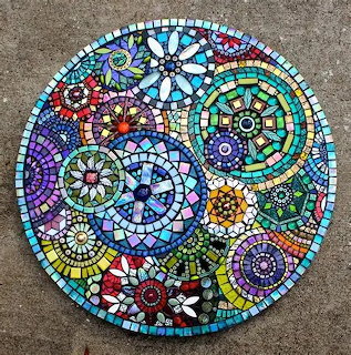 Circular mosaic artwork with colorful glass tiles arranged in floral and mandala patterns