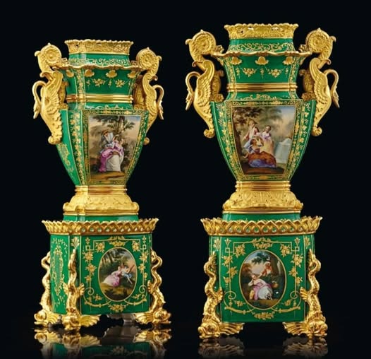 Two ornate green and gold porcelain vases with painted scenes on a black background