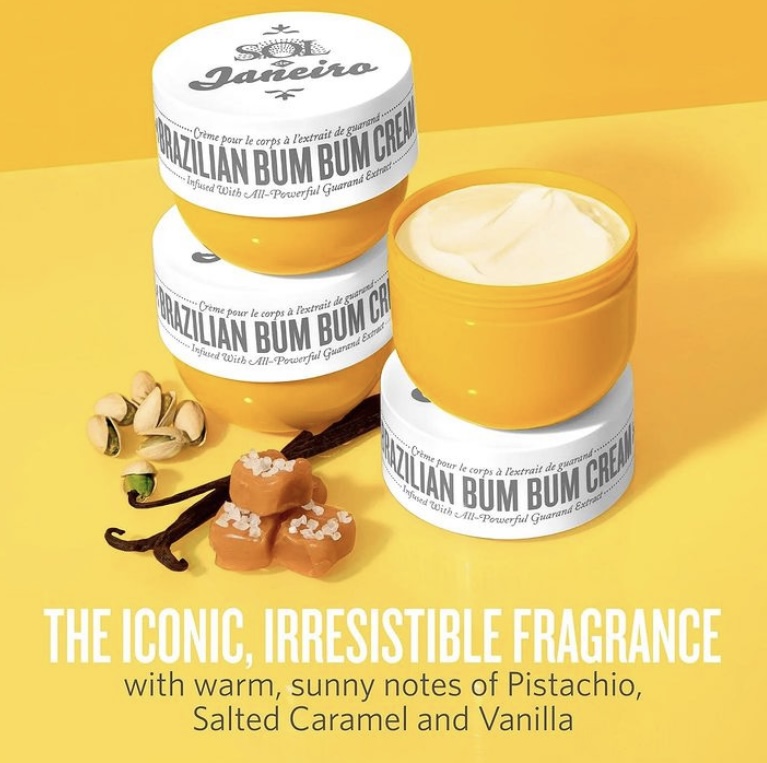 Three white cosmetic jars of Brazilian Bum Bum Cream displayed with pistachio nuts, caramel, and vanilla beans
