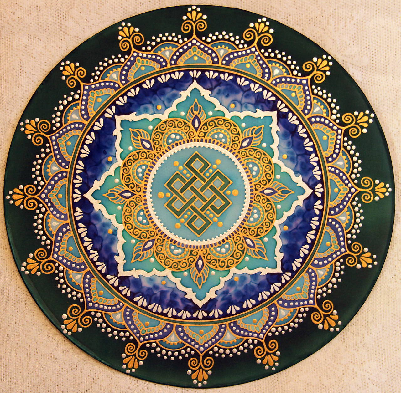 Circular mandala with gold and blue geometric patterns, central eternal knot, ornate layered borders on dark green background