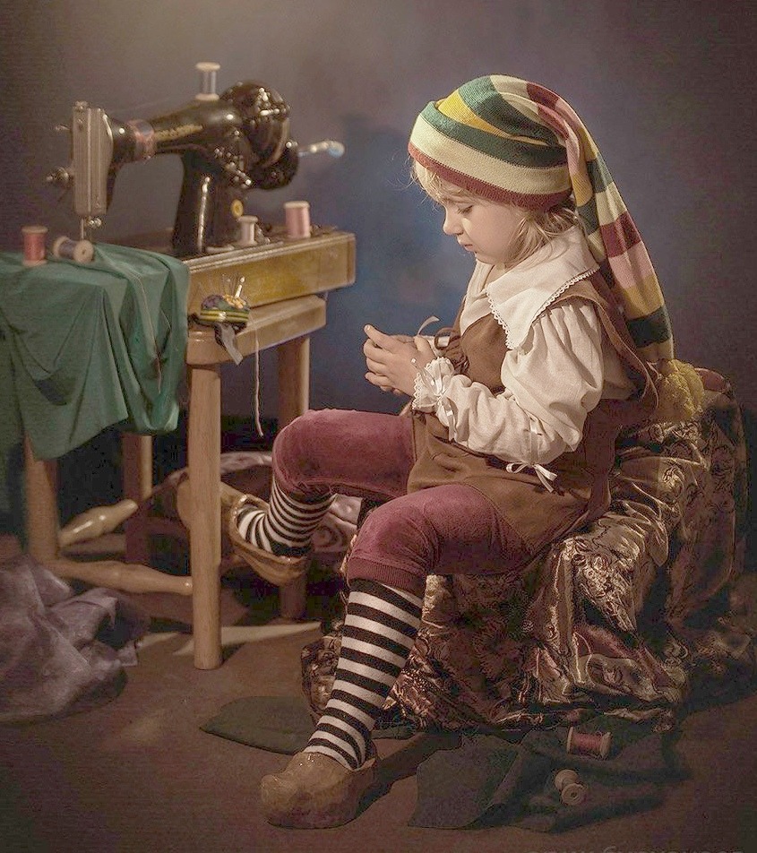 Child in striped hat and socks playing with old-fashioned mechanical toy at small wooden table