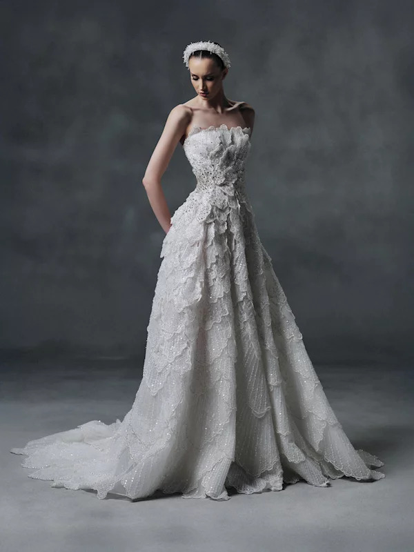 Woman in a white bridal gown posing in a studio against a dark gray background