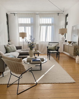 Minimalist living room with neutral furniture, wooden floors, and large windows