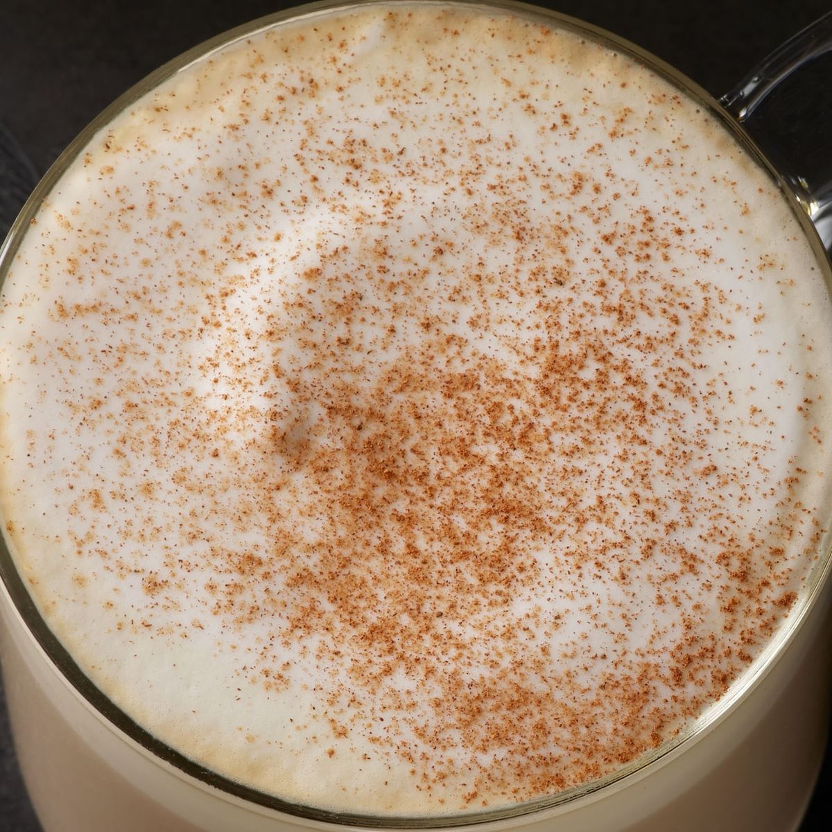 Overhead view of latte with cinnamon sprinkled on foam in white mug