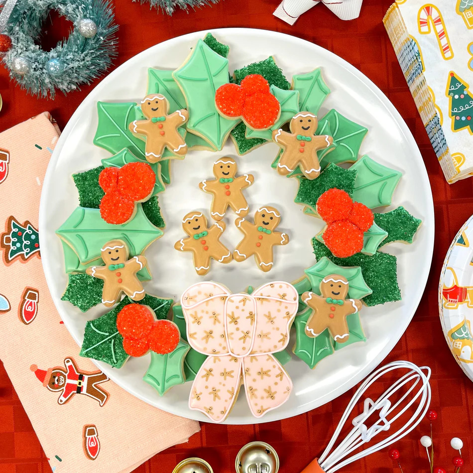 Plate of Christmas wreath cookies decorated with gingerbread men, holly leaves, red berries, and a bow