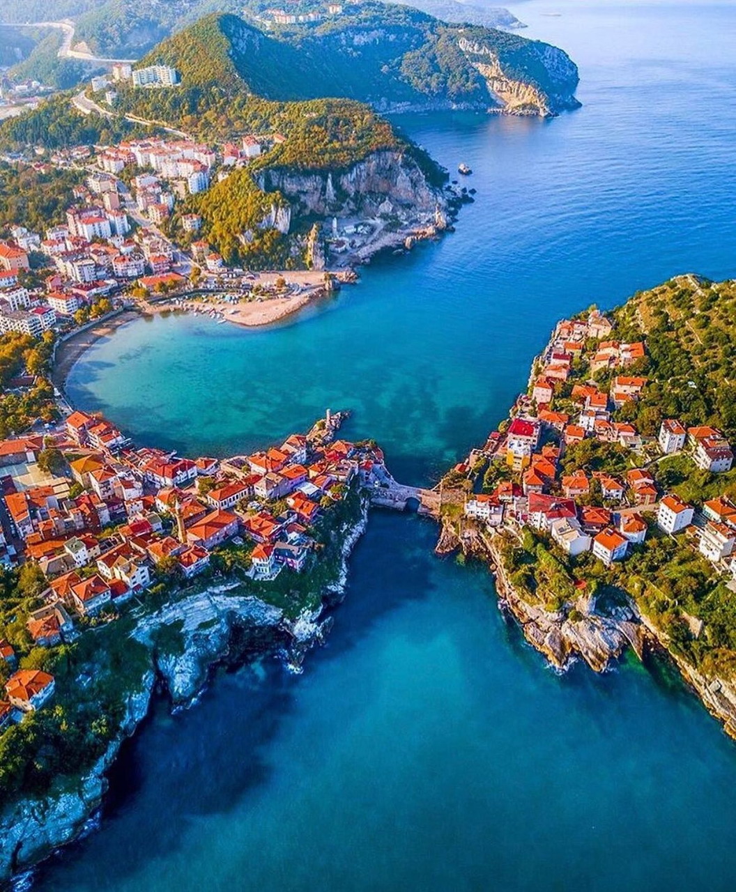 Aerial view of Amasra, Turkey with red-roofed houses around a turquoise bay and rocky coastline