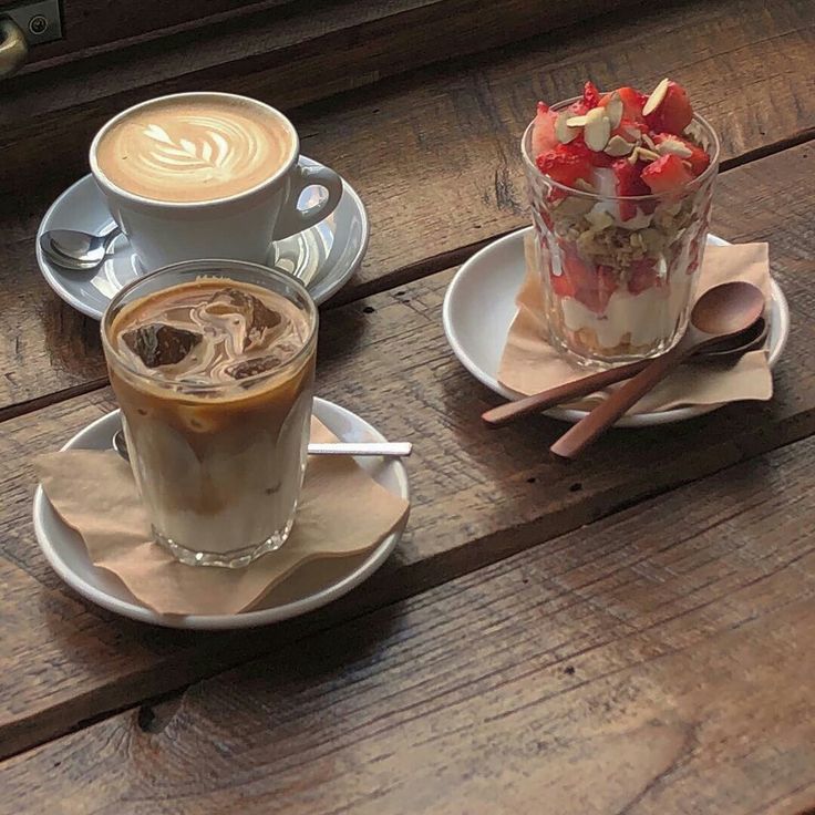 Latte, iced coffee, and strawberry parfait on a wooden cafe table
