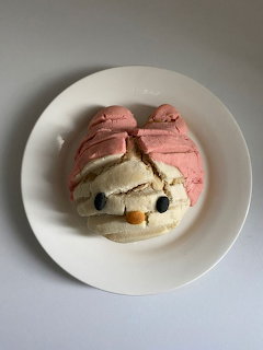 Concha pastry decorated as My Melody with pink shell topping and kawaii face on white plate