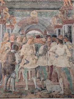 Renaissance fresco showing a group of noblemen in medieval clothing gathered in a courtly scene