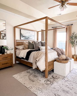 Wooden four poster canopy bed with neutral bedding in a cozy decorated bedroom