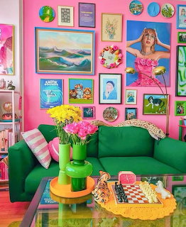 Colorful living room with pink gallery wall, green sofa, flowers, and eclectic framed artwork