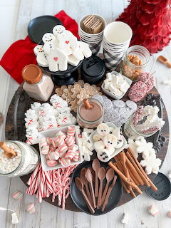 Hot chocolate bar with marshmallows, candy canes, cookies, and festive treats on a round tray