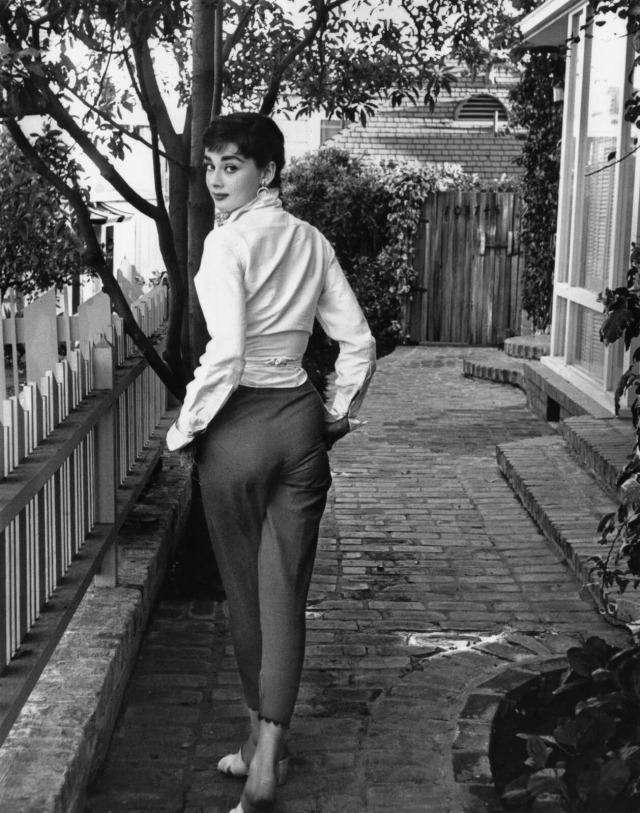 Black-and-white portrait of Audrey Hepburn on a garden path, looking back over her shoulder