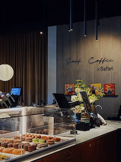 Dimly lit cafe counter with pastry display case and Surf Coffee x Safari wall sign