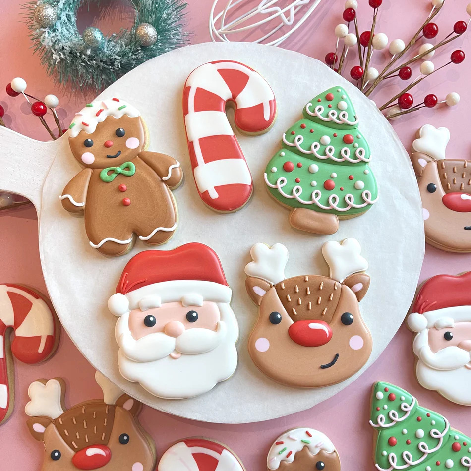 Assorted decorated Christmas cookies on white plate with festive ornaments
