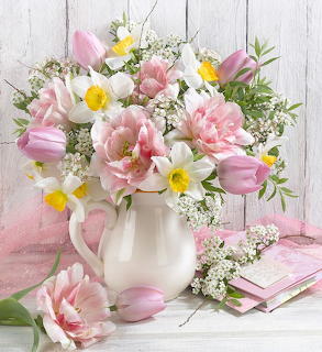 Pink tulips and white daisies in white pitcher on rustic wood background