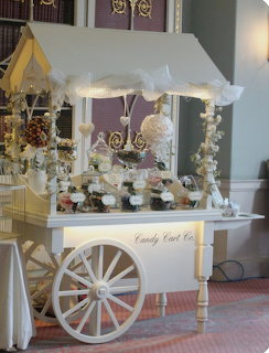 White dessert cart with cakes, flowers, and sweets in an elegant indoor setting